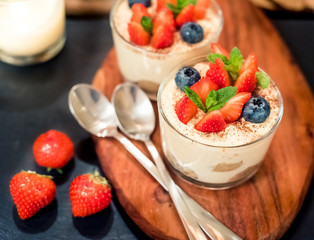 Homemade italian dessert tiramisu with strawberries, mint and blueberry in glass