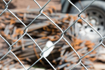 Blurry construction debris through a metal chain link fence