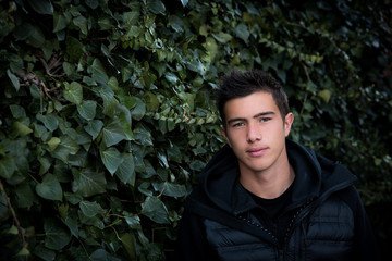 Handsome young man dressed in black, looking at camera outdoor by ivy 