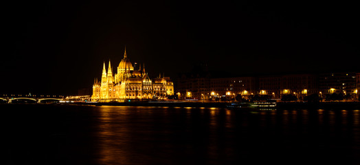 Panoramic view of Hungarian Parliament reflecting in Danube river. Night cityscape of Budapest