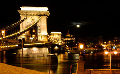 Night cityscape of Budapest with St. Stephen's Basilica, Danube river, Szechenyi Chain Bridge and full moon above the city