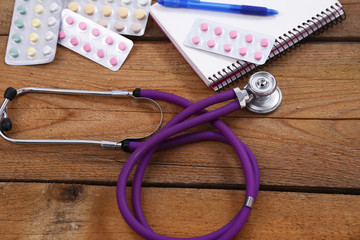 Medical stethoscope and tablets isolated on wooden background
