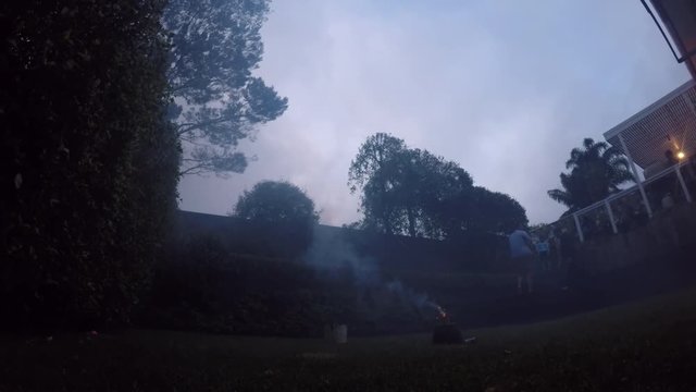 Family launching fireworks explosive pyrotechnic in slow motion in home back yard.  Real people. Copy space