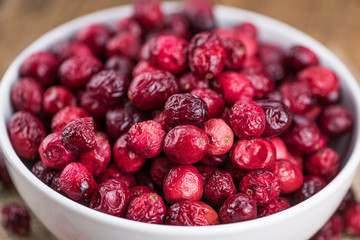 Some fresh Dried Cranberries on wooden background (selective focus; close-up shot)