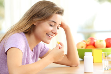 Obraz na płótnie Canvas Happy teen taking a vitamin pill at home