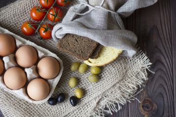 eggs, bread, olives,tomatoes and spices on a wooden table