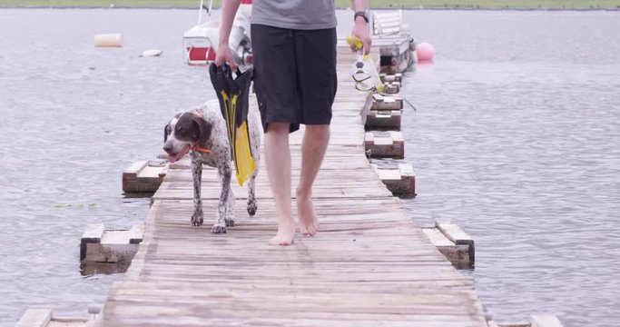 Man and his dog walking on boat dock towards camera - summer fun