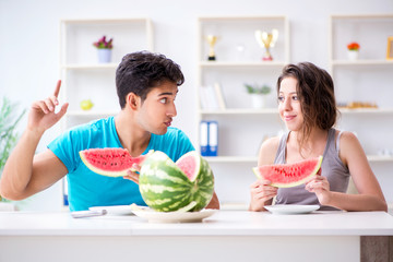 Man and woman eating watermelon at home