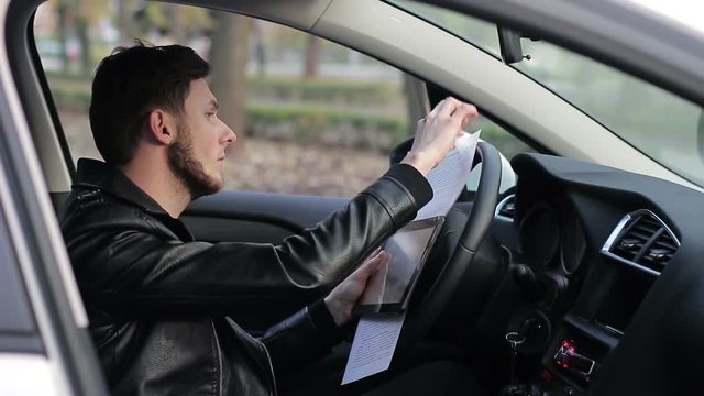 Young guy working in the car. Remote work. Online earnings. Freelancer