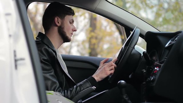 Young guy working in the car. Remote work. Online earnings. Freelancer