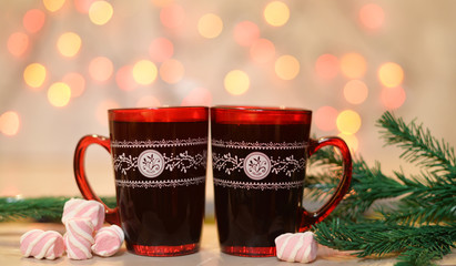 beautiful New Year red cup with hot drink coffee, tea near Christmas tree on the bokeh background