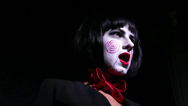pretty woman in horror style make up sings a song on dark background