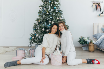 Two happy, stylish and beautiful girls opened Christmas gifts and received a the rabbit.