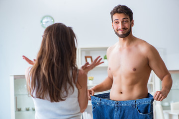 Man in oversized pants in weight loss concept with girlfriend wi