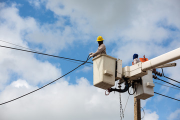 electricians repairing wire of the power line on electric power pole
