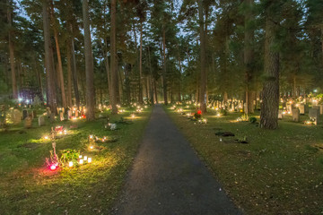 Gravar i skogen fotat på Allhelgonanatten med alla sin tänd ljus till minne av någon