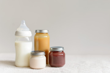Bottles of milk and puree for baby over blurred background with free copy space