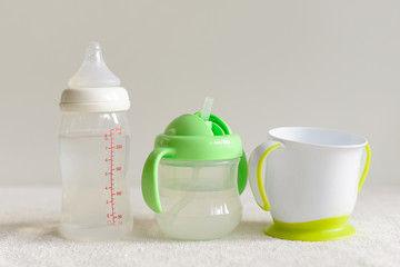 Three kinds of bottles and cups with water for baby. - 179630537