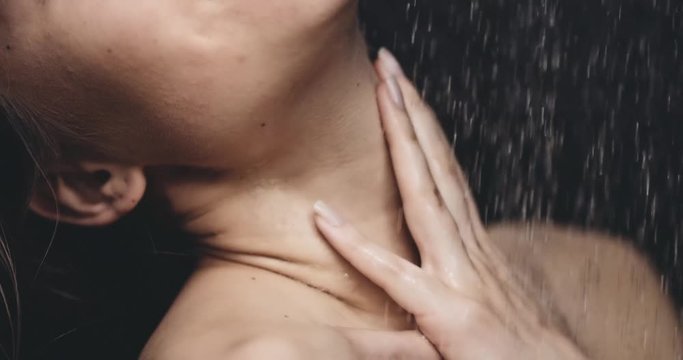 Woman taking shower in slow motion 120fps. dolly shot. Young beautiful woman taking a shower gently touching her skin. Close up on neck and shoulder. Beauty and relax concept. Filmed in 4K DCi RAW.
