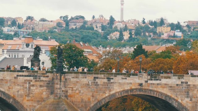 Prague Charles Bridge on Vltava River on which crowds of tourists stroll