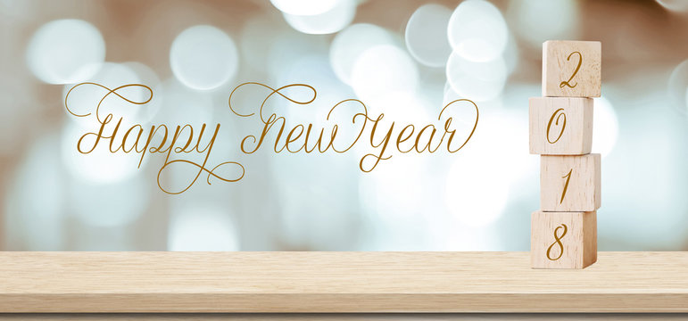 Wooden cubes with 2018 and happy new year over blur bokeh background, banner with copy space for text, new year greeting card template