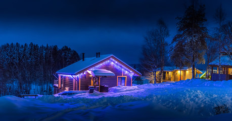 A country house decorated with a light garland. Cottage in the wild in winter.