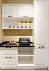 Fototapeta premium Modern kitchen furniture with contemporary kitchenware like hood, black induction stove and oven in house.