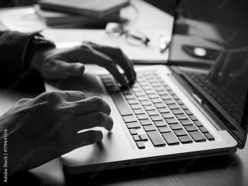 Wall mural close up of businessman using laptop on the office desk. black and white tone