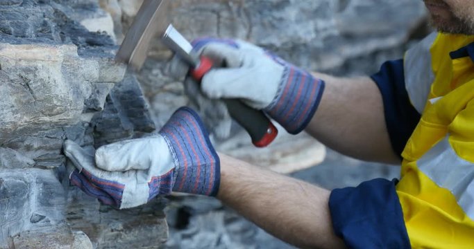 Close up of Geologist hand taking rock sample with pick axe mining exploration 