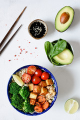 Buddha bowl healthy vegetarian salad with broccoli, wild rice, tofu, carrot, avocado, sprout chickpea and cherry tomato on white background. Asian cuisine