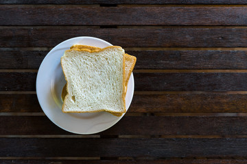 Sliced bread in white plate on wooden table. Breakfast meal.