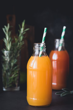 Detox citrus juices in bottle with drinking straw over dark background. Fresh orange and grapefruit juice. Selective focus, toned image