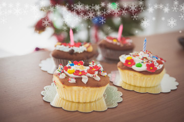 Christmas cup cake on wooden table with decorated Christmas tree background