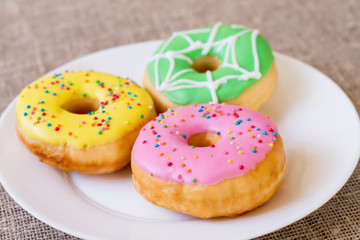 Donuts with a glaze on a white plate. Colored sweet donuts