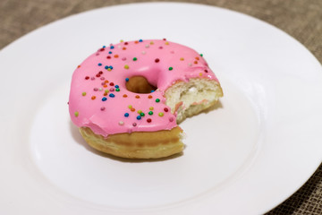 Donuts with a glaze on a white plate. Colored sweet donuts