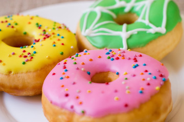 Donuts with a glaze on a white plate. Colored sweet donuts