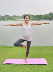 Fototapeta premium Pregnant woman doing yoga in the public park.