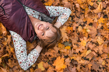 Attractive woman is lying over autumn leaves in park