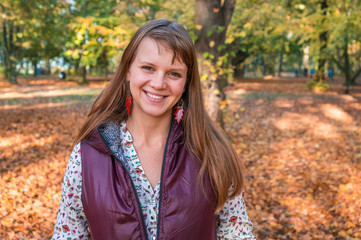 Fototapeta premium Smiling woman in park on sunny autumn day