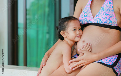 Little Child Girl Listening Belly Of Pregnant Women In Hot