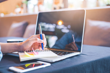 Woman hand is writing on a note pad with a pen in the office.