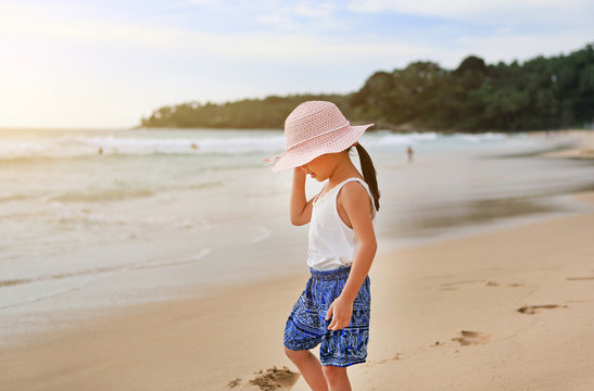 Portrait of cute little asian girl wear straw hat on the beach.