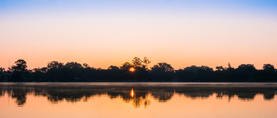 The panoramic silhouette landscape of lake at Pindaya town, Myanmar in the morning time with the sunrise and the mirror lake
