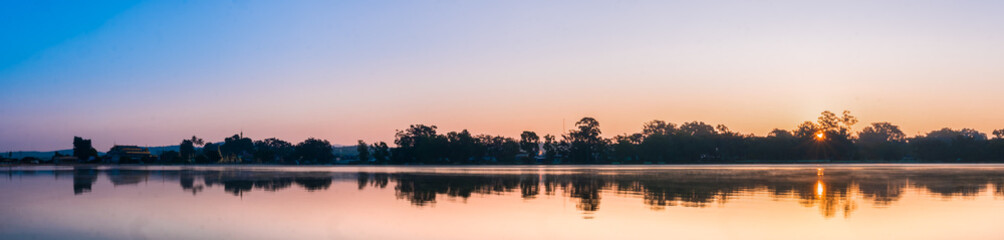 Fototapeta premium The panoramic silhouette landscape of lake at Pindaya town, Myanmar in the morning time with the sunrise and the mirror lake