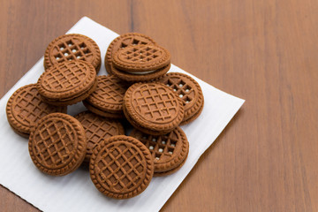 Chocolate cookies with cream filling on wooden table