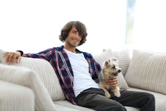 stylish guy sitting on the couch with his dog.