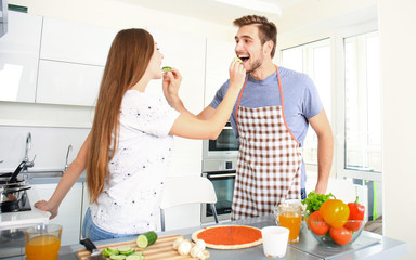 Young couple making pizza in kitchen together.