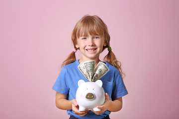 Fototapeta na wymiar Cute little girl with piggy bank on color background