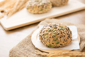 A healthy multigrain bread bun on a wooden plate in a bakery