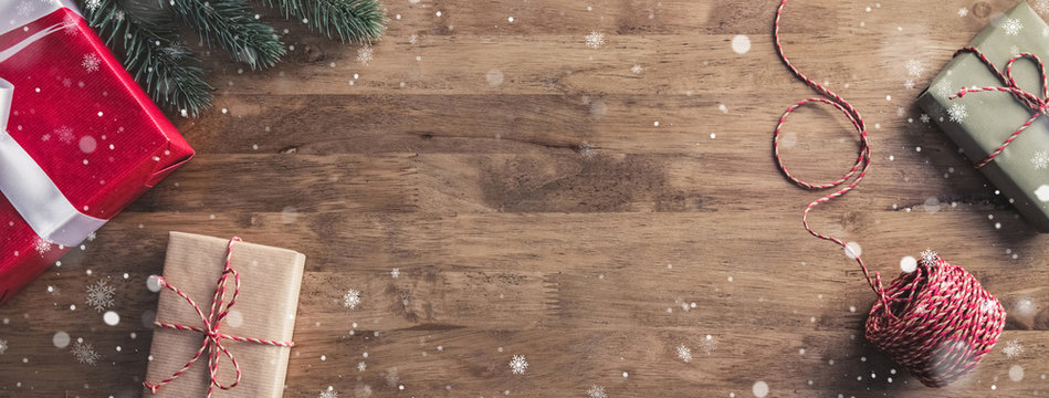 Snow flakes falling upon gift boxes on a wooden table - Christmas banner with copy space